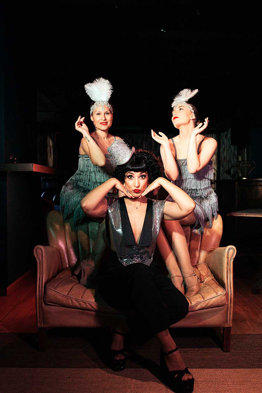 Sing-Swing-900×1350 Trío de vocalistas y bailarinas pin-up posando en ambiente teatral vintage, estilo fiesta gatsby