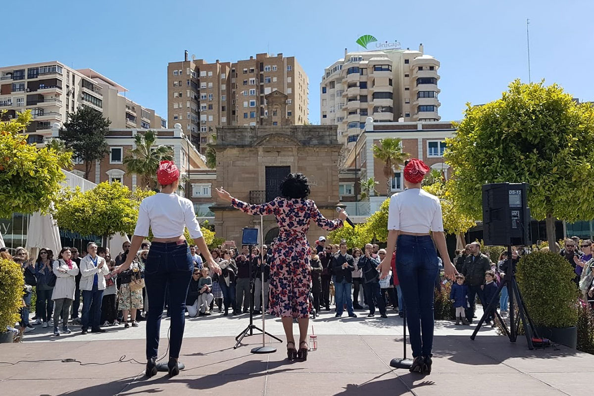 The-Vintage-Experience-Actuacion-13 Trío vocal y bailarinas pin-up actuando en plaza urbana ante público durante evento cultural en Muelle Uno, Málaga